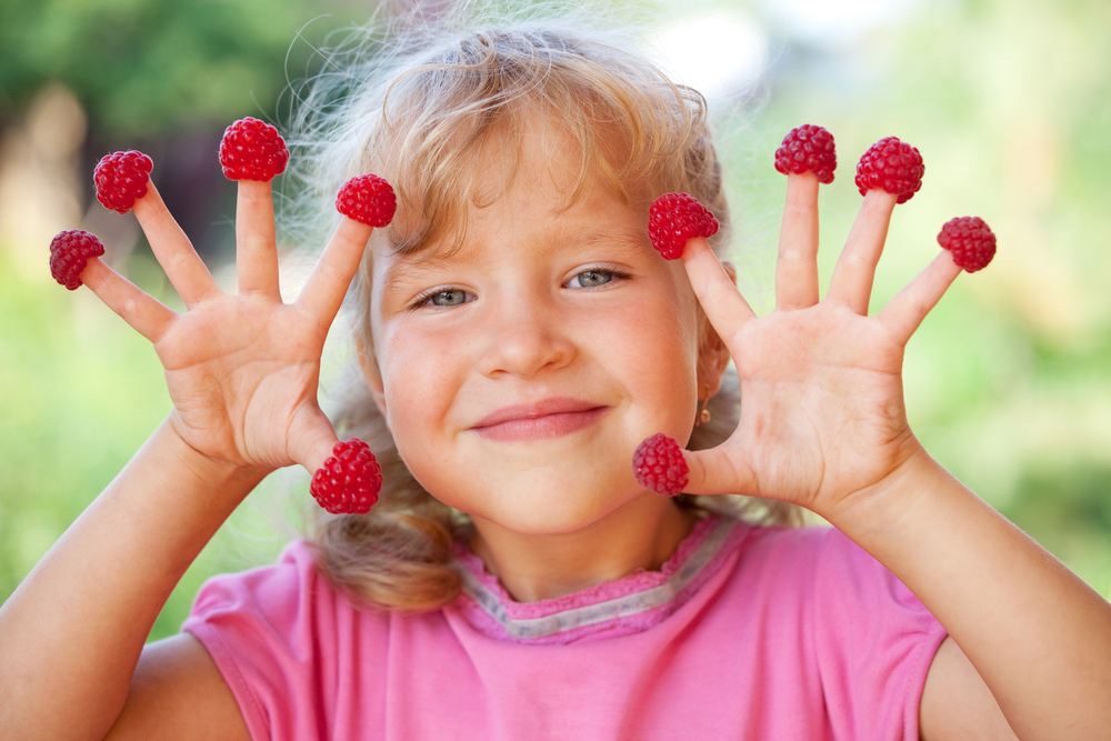 Little girl with raspberry