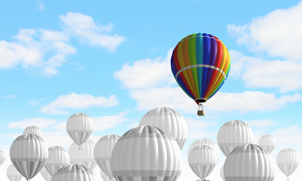 A colorful hot air balloon rising above a sea of white hot air balloons