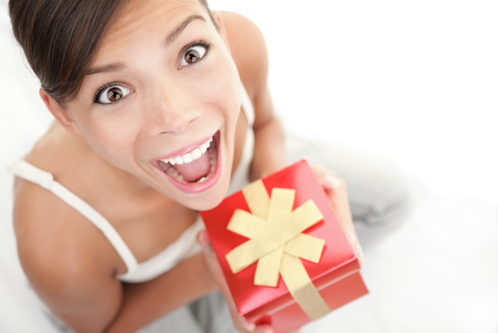 A woman is excited about the gift she is holding