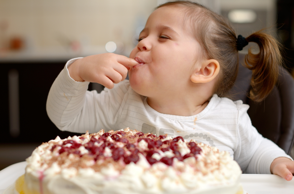 Cute little girl tasting cake