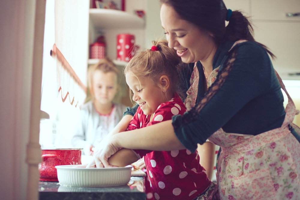 Mother with her 5 years old kids cooking a holiday pie in the kitchen