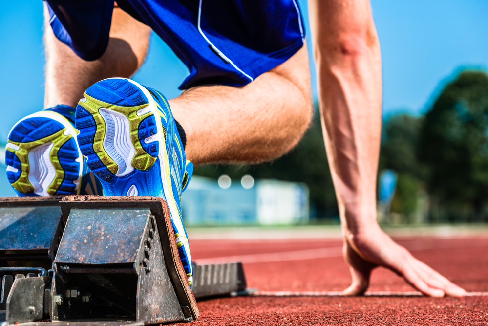 Runner before start signal on starting block of sprint track in sport stadium