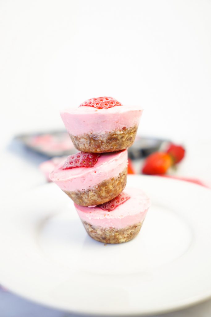 A stack of three vegan strawberry cheesecake tarts on a white plate
