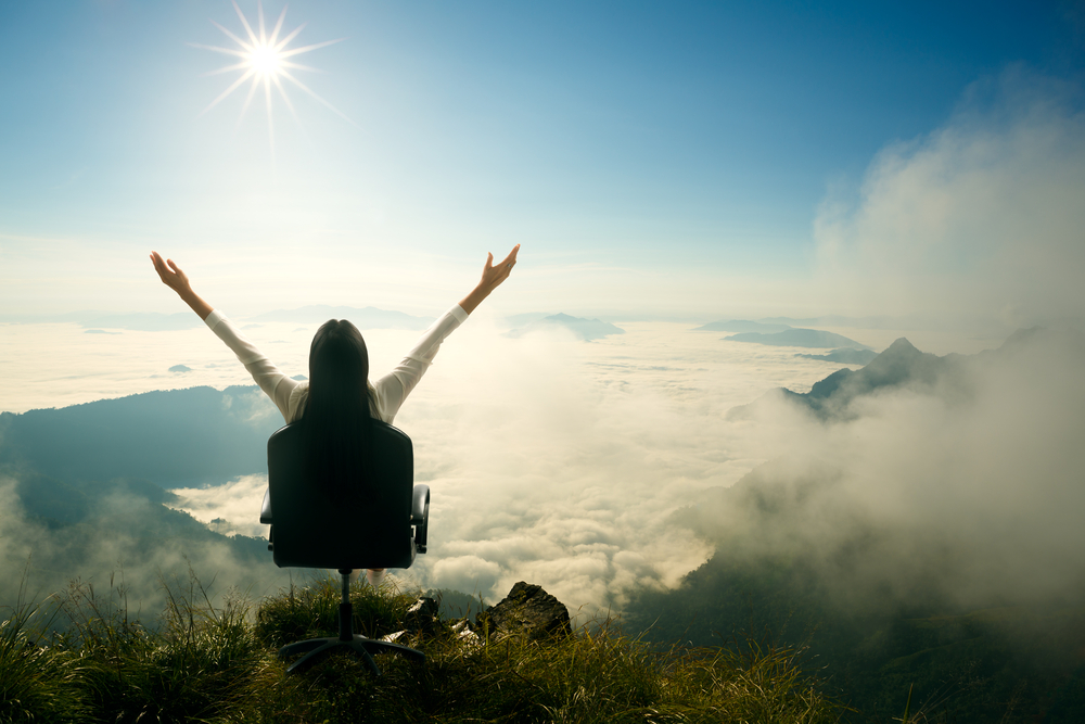 Young woman sits on a chair and open her arms at the top of the