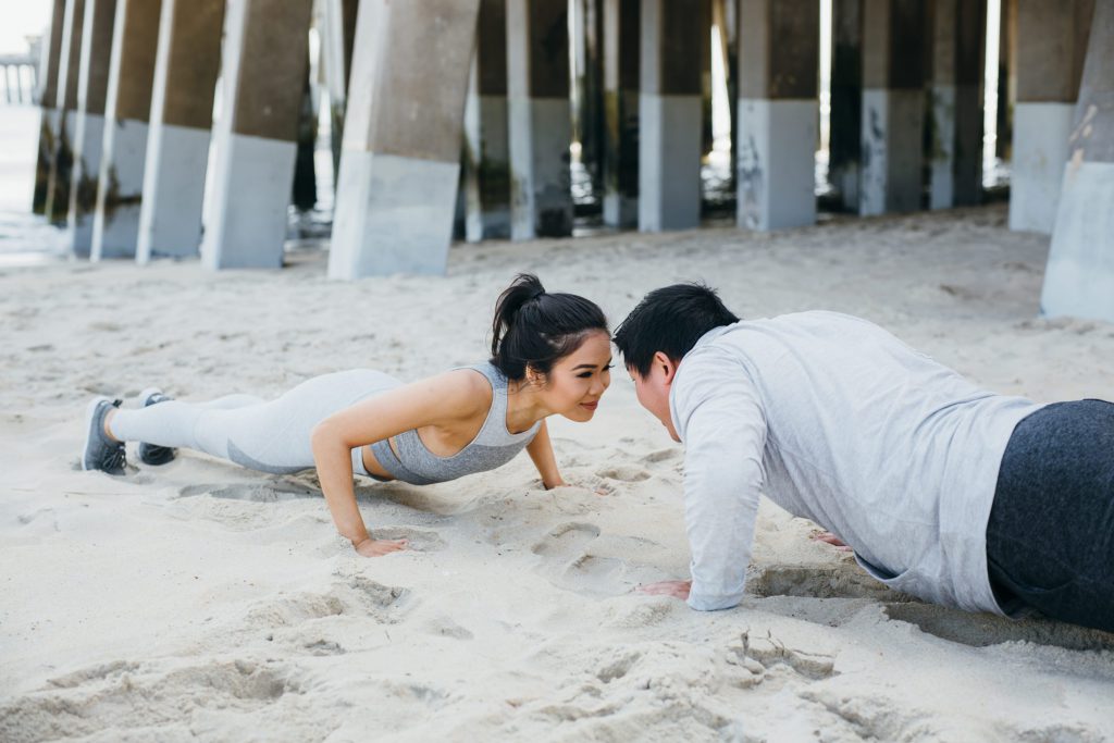 A happy couple doing planks on the beach