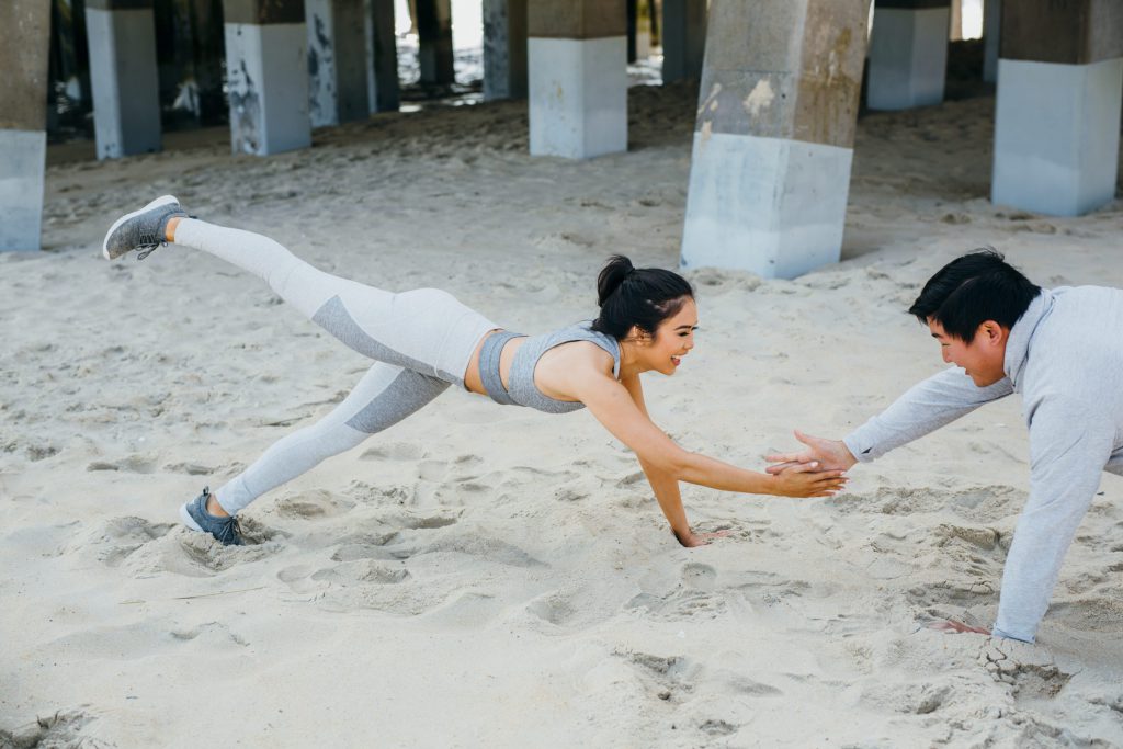 A happy couple doing planks on the beach