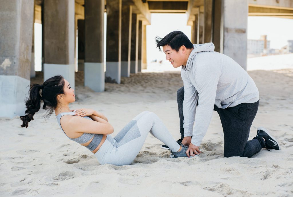 A couple is doing ab exercises on the beach