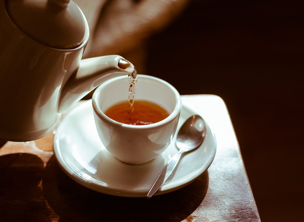 A kettle pouring tea into a teacup