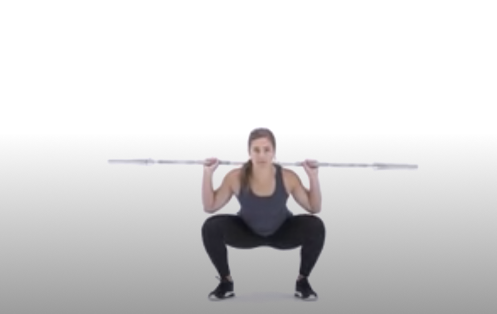 a woman doing a barbell squat