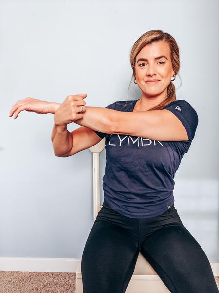 A woman is performing a deltoid stretch