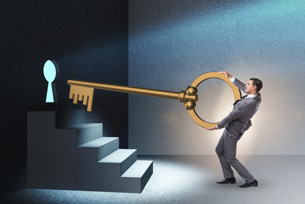 A businessman is holding a large key near a keyhole concept