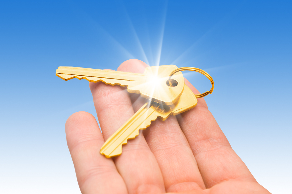 two gold keys on a palm over blue background