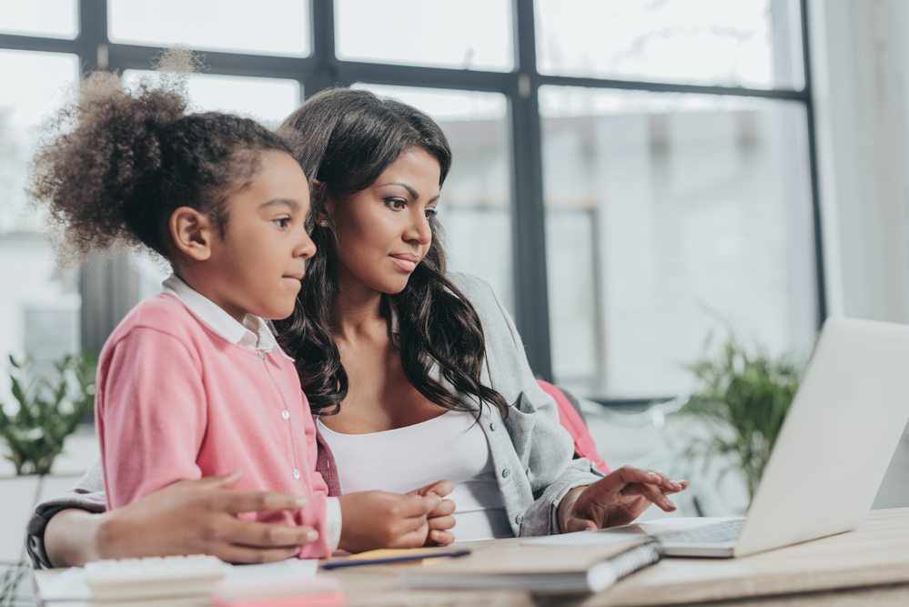 A mother is working while her daughter tries to get her attention.