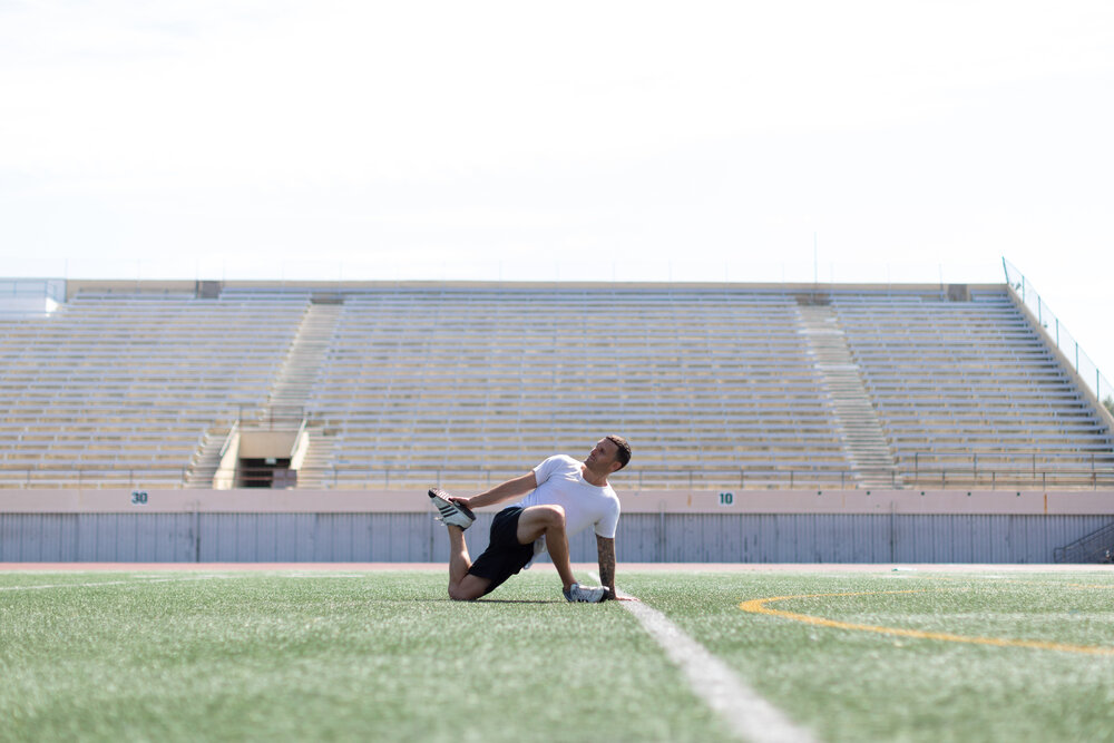 Man on field stretching his knees