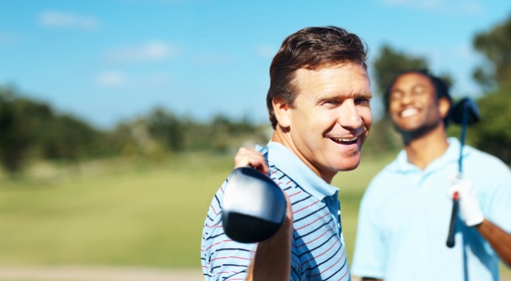 A man smiling with his club resting on his shoulders.