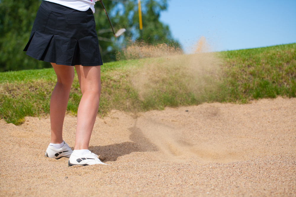 A golfer strikes a tee shot on a beautiful park near lake