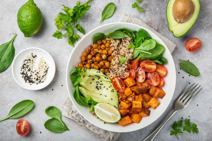 healthy vegan lunch bowl with ingredients. Avocado, quinoa, sweet potato, tomato, spinach and chickpeas vegetables salad. Top view