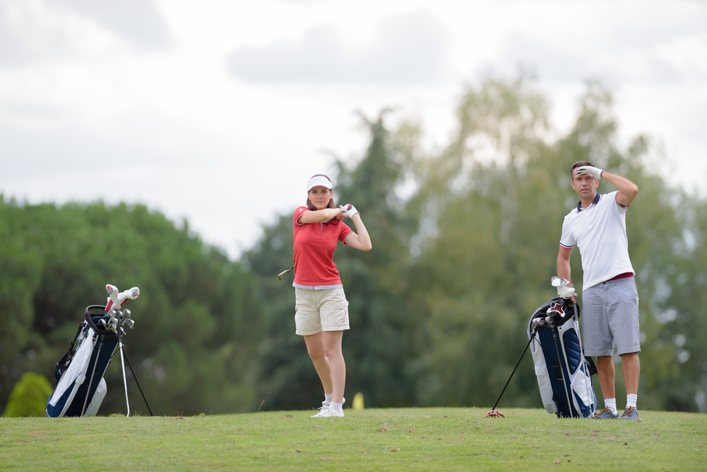 A couple is teeing off at the golf course