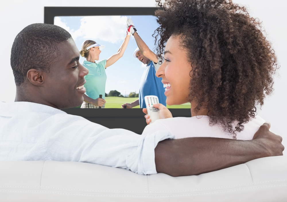 Couple smiling while watching golf on television at home
