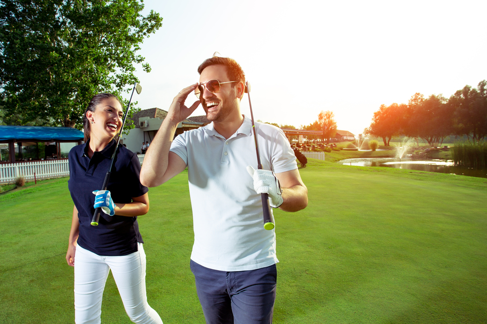 A happy couple walking on the golf course.