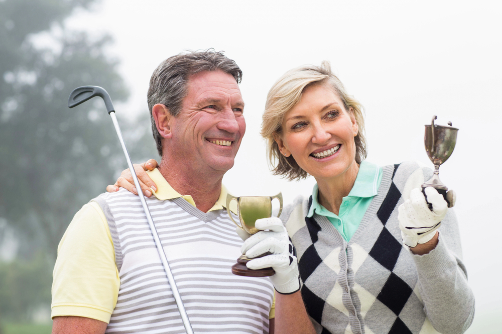 Male and female golfers holding trophies and celebrating success after a golf competition.